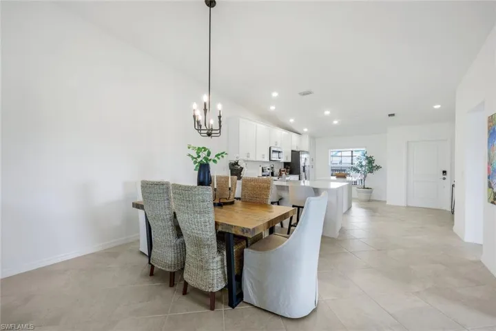 Dining space with light tile patterned flooring, recessed lighting, lofted ceiling, and a chandelier