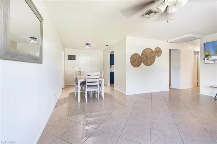 Spacious room with neutral tile flooring, white walls, a multi-pane window, and a ceiling fan