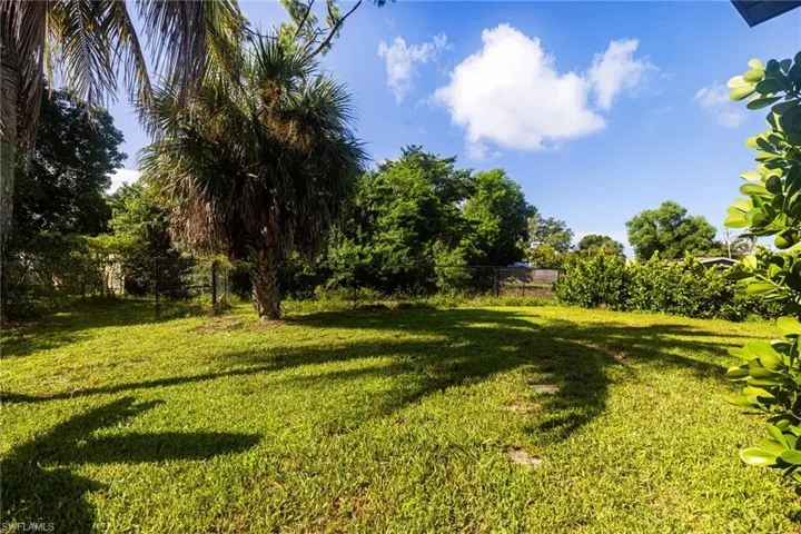 Screened lanai with concrete flooring, exposed wood beam ceiling, and direct access to a spacious grassy yard