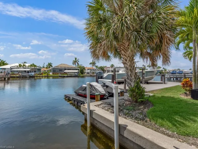 Dock area with boat lift, a water view, a lawn, and a residential view