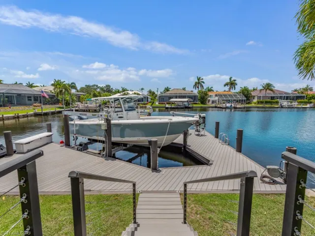 Dock area with boat lift, a water view, and a residential view