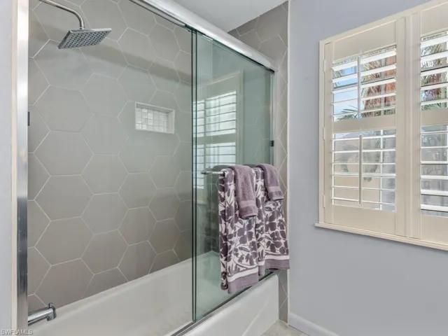 Bathroom featuring combined bath / shower with glass door and baseboards