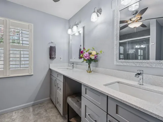 Bathroom with a ceiling fan, double vanity, and a shower with door
