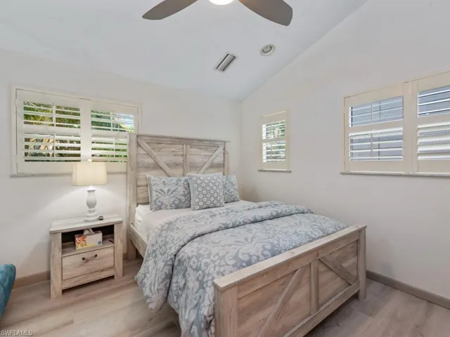 Bedroom with wood finished floors, lofted ceiling, and a ceiling fan