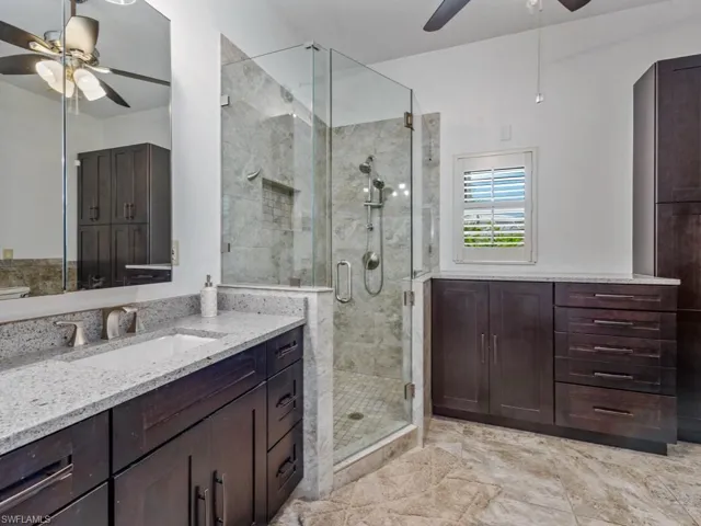 Full bathroom with a ceiling fan, vanity, and a stall shower