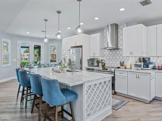 Kitchen featuring appliances with stainless steel finishes, wall chimney range hood, healthy amount of natural light, decorative backsplash, and recessed lighting