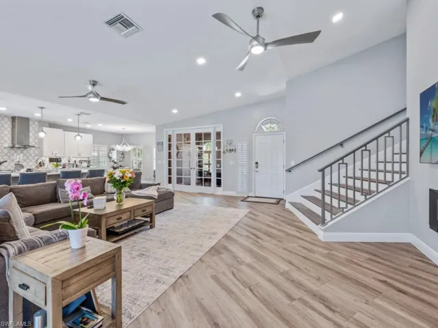 Living area with ceiling fan, recessed lighting, light wood finished floors, stairway, and vaulted ceiling