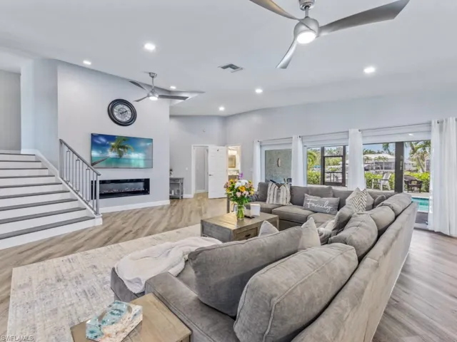 Living area with ceiling fan, recessed lighting, wood finished floors, and a glass covered fireplace