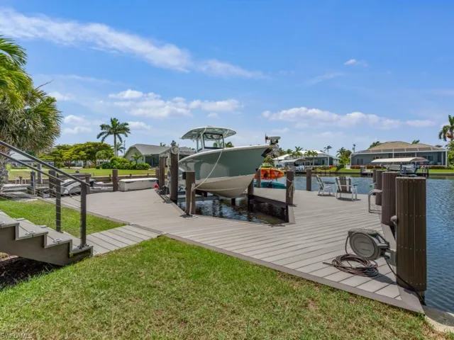Dock with boat lift, a lawn, and a water view