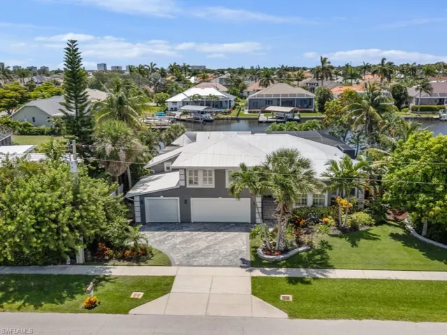 View of front of home with a garage, driveway, a front yard, a residential view, and a water view