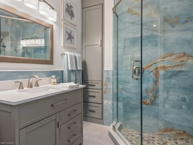 Full bath with a stall shower, vanity, tile walls, and tile patterned floors