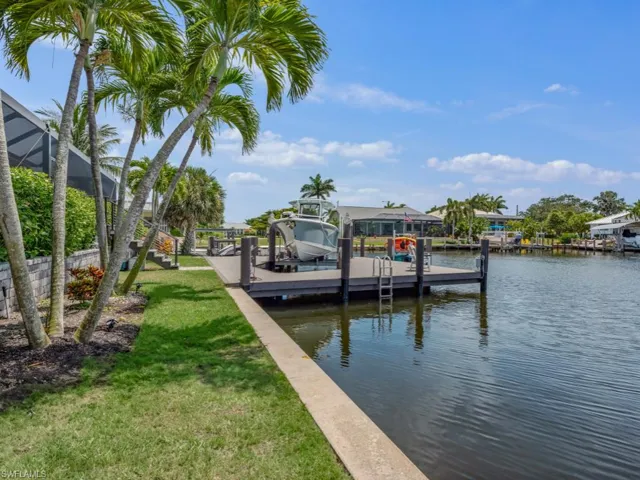 Dock area with boat lift, a water view, and a lawn