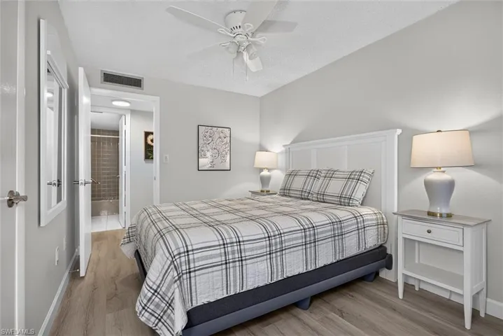 Guest Bedroom featuring wood-finish flooring, a white paneled headboard, and light gray painted walls
