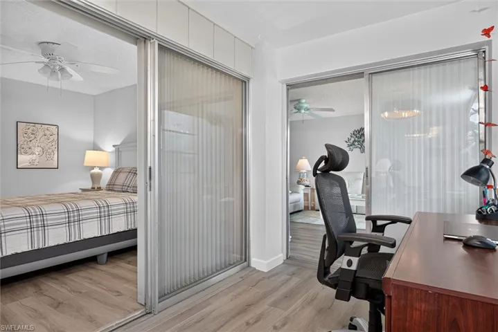 Light-toned wood-finish flooring extends throughout these interior spaces, featuring sliding privacy panels with vertical blinds