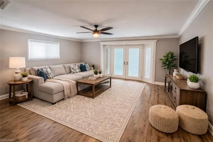Some pictures virtually stagedLiving area featuring ornamental molding, a ceiling fan, wood-type flooring, and french doors