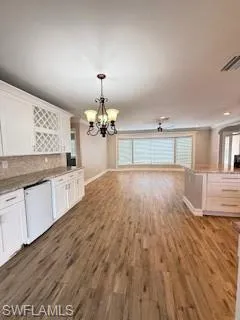 Unfurnished dining area with dark wood-style flooring and hanging lights