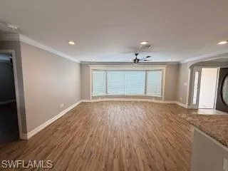 Unfurnished living room with ornamental molding, wood finished floors, and recessed lighting