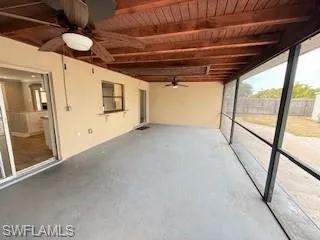 Unfurnished sunroom with a ceiling fan and a patio area