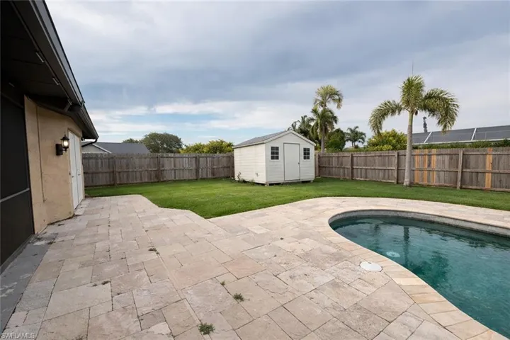 View of swimming pool with patio surround, a fenced backyard, and a storage shed Some pictures virtually staged