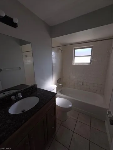 Bathroom featuring vanity, shower / washtub combination, and light tile patterned flooring