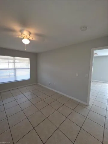 Empty room featuring light tile patterned flooring and a smoke detector