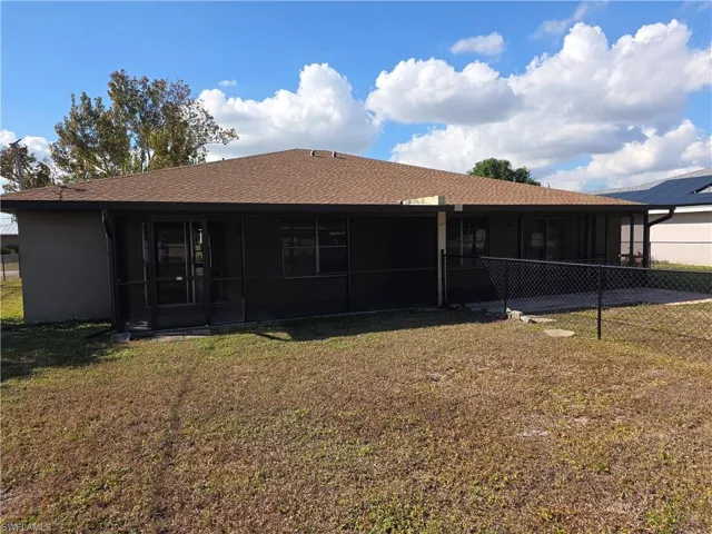 Back of house with a yard, a sunroom, and a shingled roof