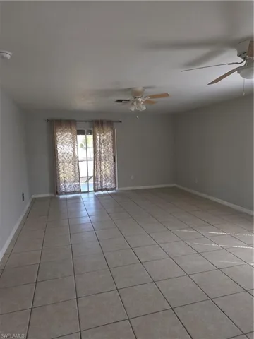 Empty room with light tile patterned floors and ceiling fan