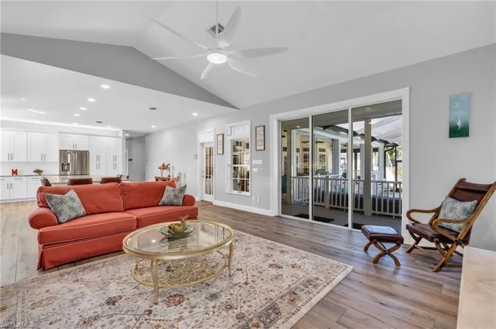 Living room with vaulted ceiling, light  wood-look floors, and ceiling fan