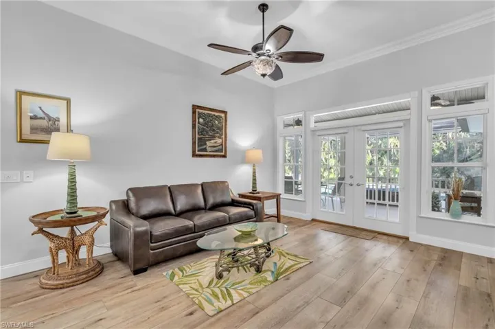 Living room featuring ornamental molding, french doors, light wood-look flooring, and ceiling fan