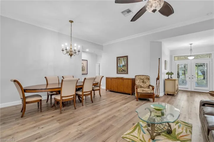 Dining area featuring crown molding, ceiling fan with notable chandelier, and light wood-Look flooring