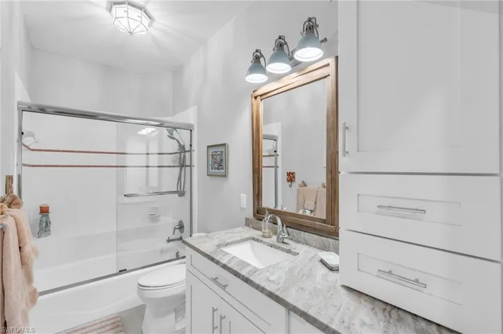 Full bathroom with vanity, enclosed tub / shower combo, and toilet