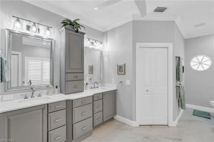 Bathroom with Dual vanity, ornamental molding, and second walk in California Closet