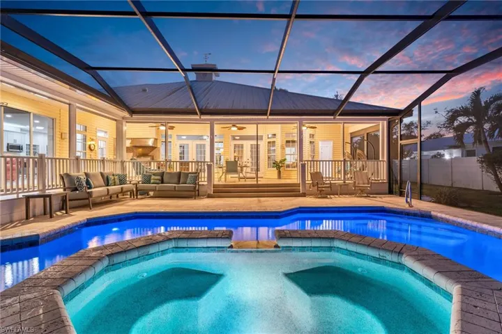 Pool at dusk with screened  lanai, a Spa, and outdoor lounge area