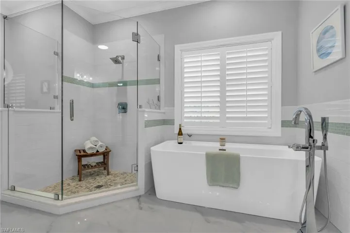 Bathroom with tile walls, ornamental molding, and shower with separate Soaking bathtub