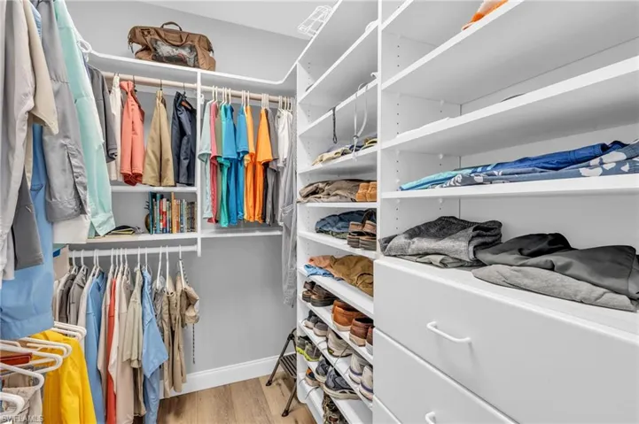 Walk in closet featuring California Closet and  light wood-look flooring