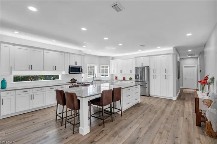 New Kitchen with light / wood-look flooring, white cabinetry, a center island, with Build in Storage and stainless steel appliances