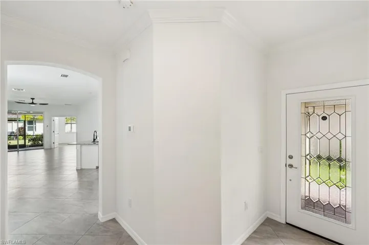 Entrance foyer featuring ornamental molding, a ceiling fan, light tile patterned floors, and arched walkways