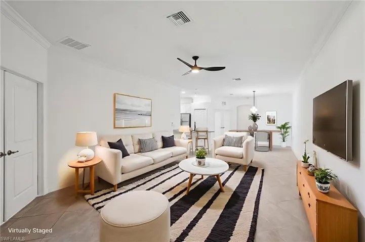 Living room featuring ornamental molding, light tile patterned flooring, and ceiling fan