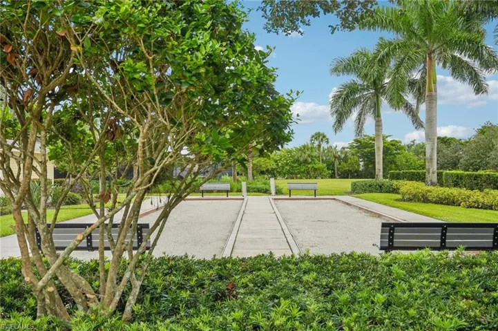 View of home's community with a bocce ball area, a lawn, and view of wooded area