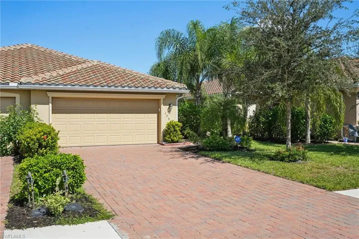 View of front of property with stucco siding, a tile roof, decorative driveway, and a front yard