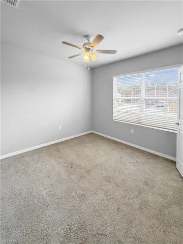 Unfurnished room with light colored carpet and a ceiling fan