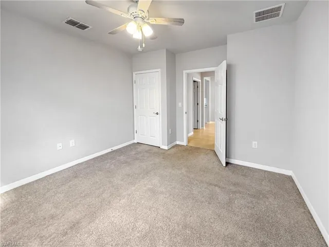 Unfurnished bedroom with ceiling fan and light colored carpet