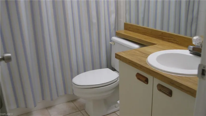 Guest Bathroom with tile patterned flooring, sink, a tub/shower with curtain, and toilet