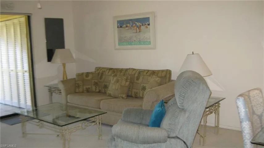 View of carpeted living room with sliders to the back screened lanai.