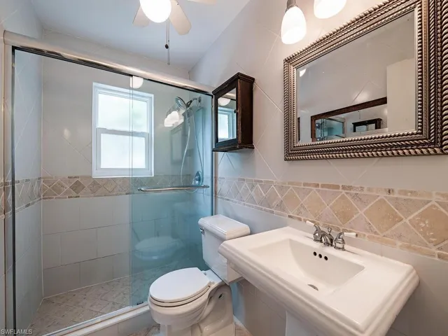 Bathroom with ceiling fan, walk in shower, tile walls, toilet, and backsplash