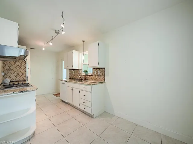 Kitchen with decorative backsplash, dishwasher, light tile patterned flooring, and white cabinets
