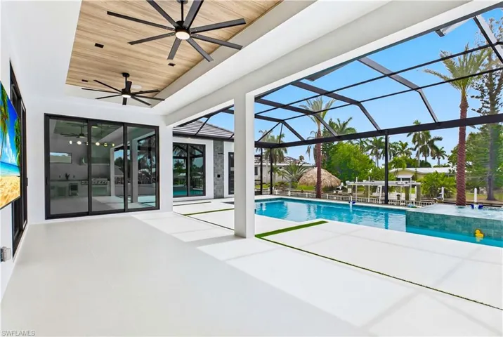 Step outside to your WATERFRONT PROMENADE w/ OVERSIZED HEATED SALTWATER POOL & SPA, MARBLE PAVERS, artificial turf, LUSH LANDSCAPING & fenced yard