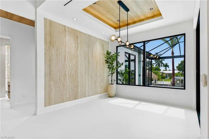 SOPHISTICATED FORMAL DINING w/ TRAVERTINE FEATURE WALL, wood ceiling, designer lighting, and 9-ft tinted Low-E sliders plus oversized windows to the WATERFRONTAGE offering views of COLONY CANAL, SPA & POOL & DOCK