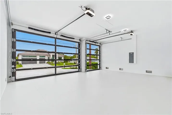 Spacious 3-car garage featuring modern glass-panel doors, epoxy-style flooring, and ample room for vehicles, storage, and recreational gear