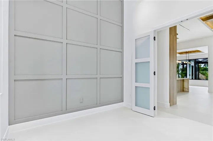 Private office/den featuring soaring ceilings, designer wall detailing, and oversized windows that fill the space with natural light!